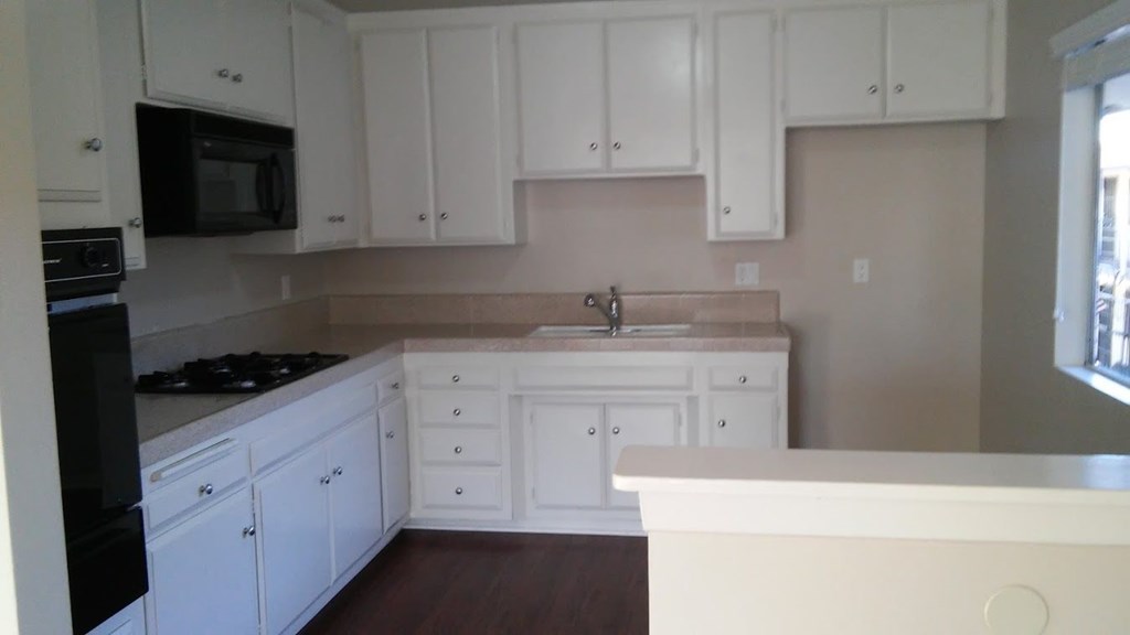 an empty kitchen with white cabinets and a sink
